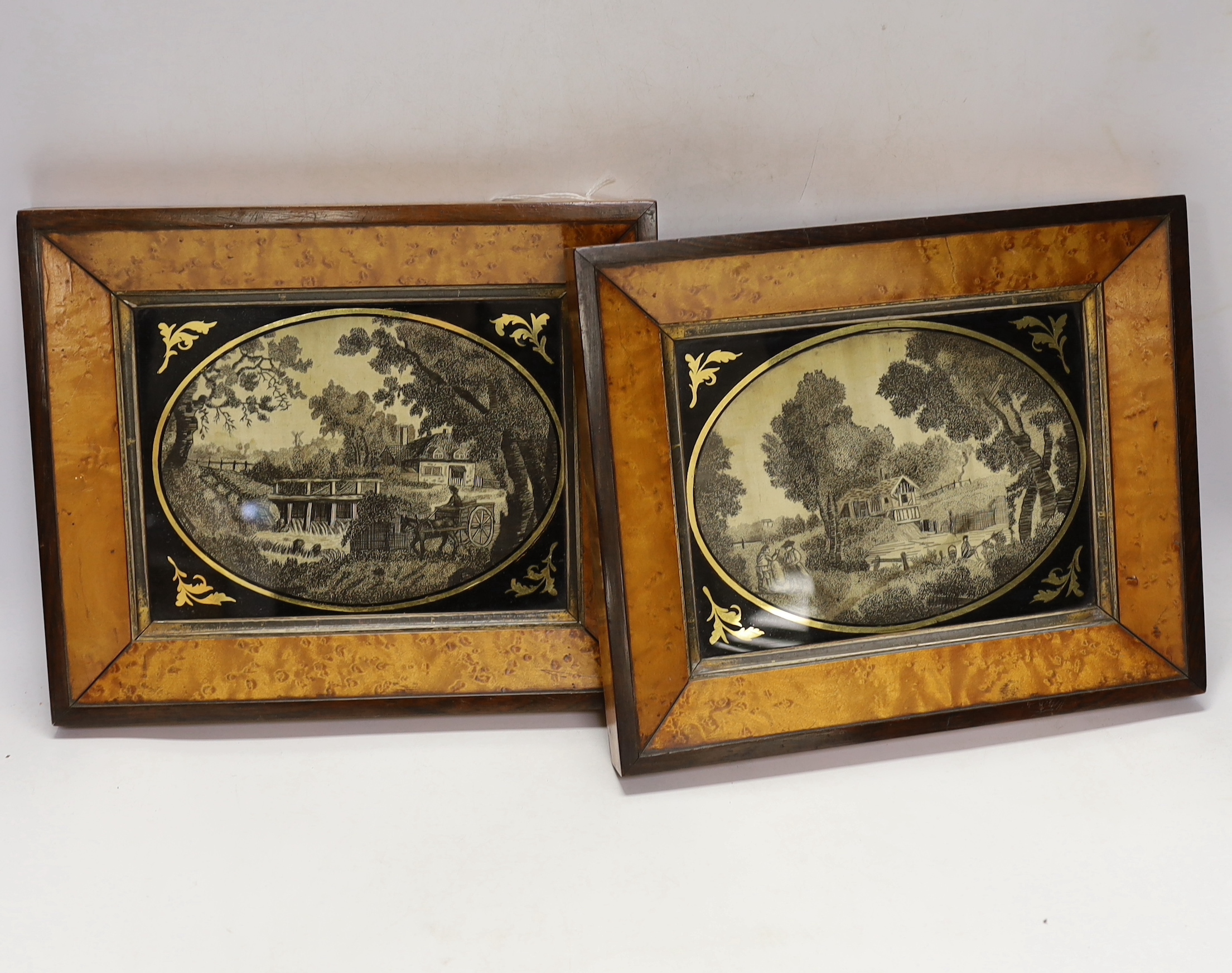 A pair of maple framed and oval verre eglomise glass Regency black silk embroidered pictorial landscape panels, 19cm wide x 14cm high